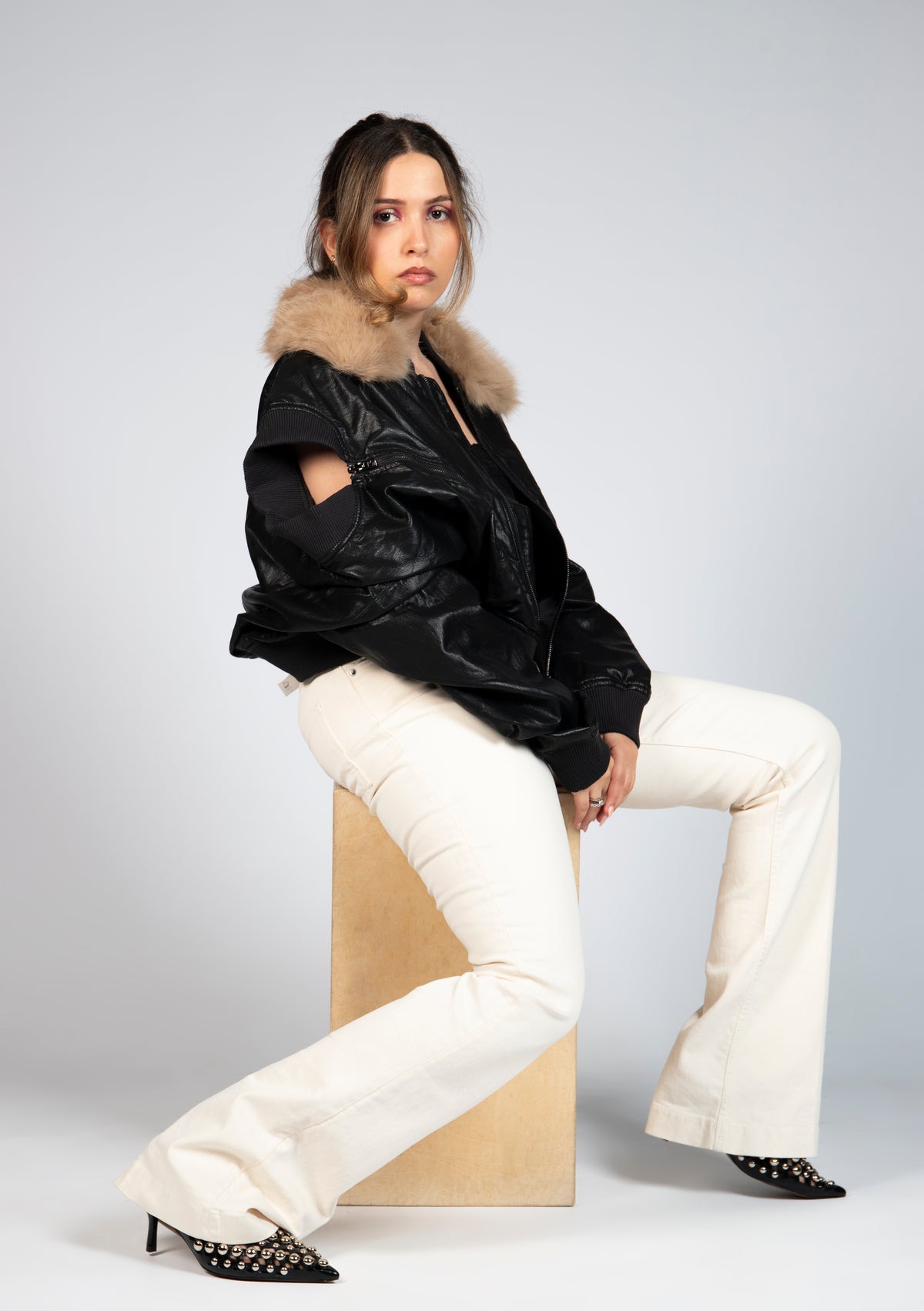 Side view of MINASEONG black faux leather bomber jacket with faux fur collar on model